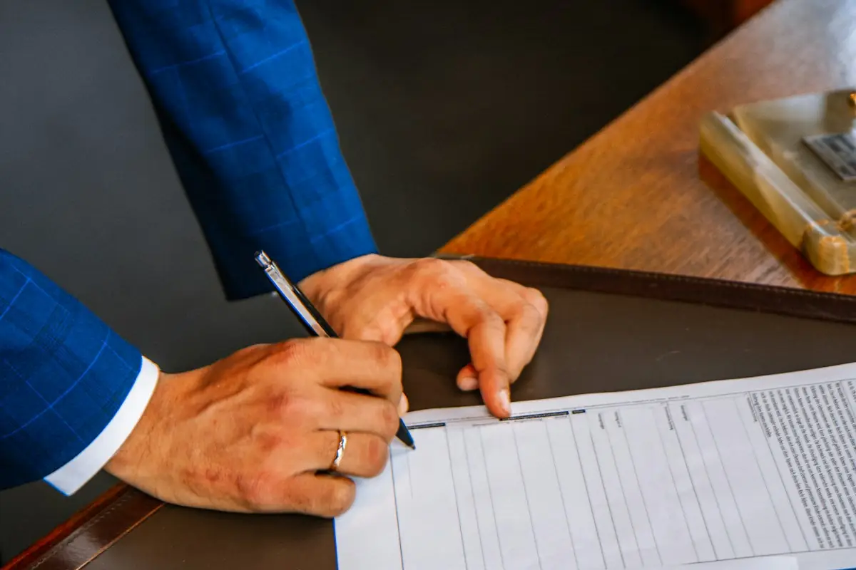 A hand completing a printed form at a desk