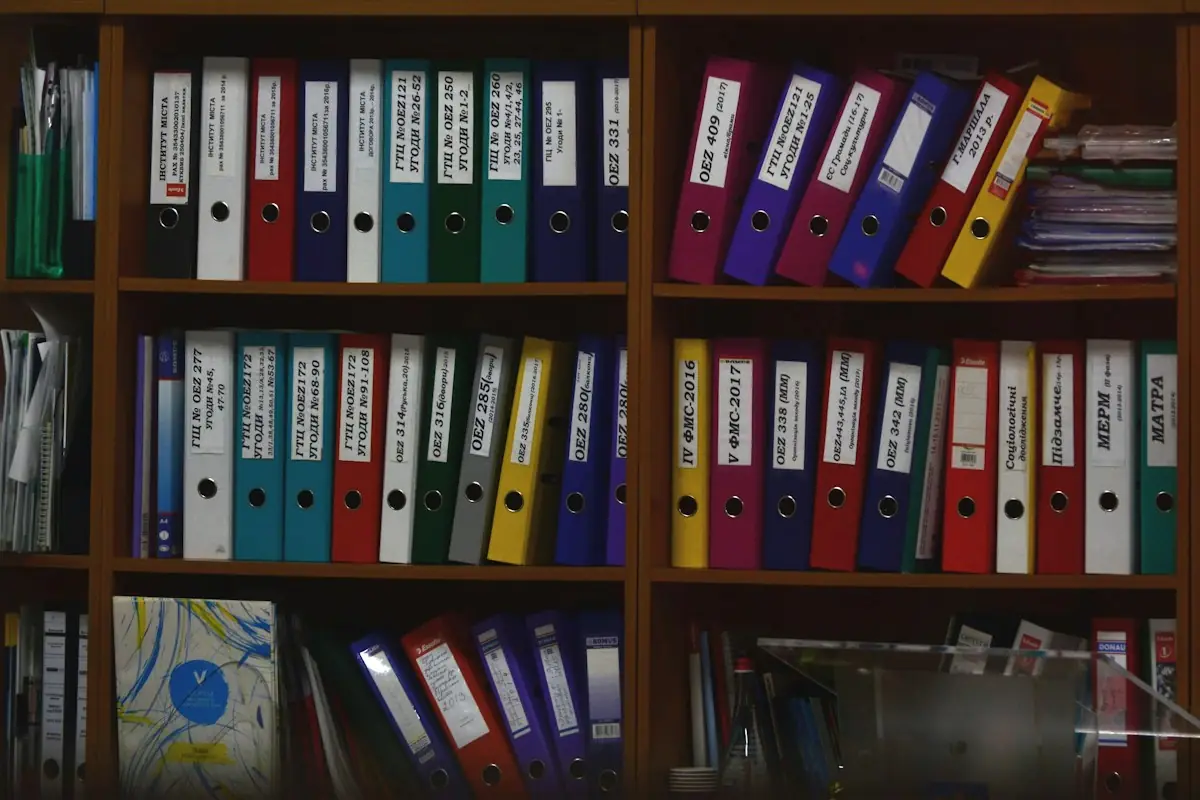 Rows of labelled ring binders on wooden shelves